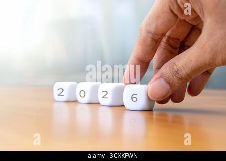 Closeup image of hand arrange a white cube with the number 2026. New year concept. Stock Photo