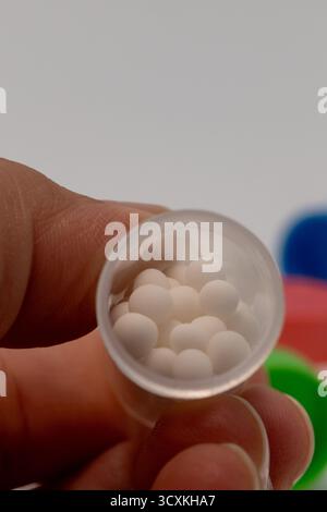 Close up shot of a hand holding plastic bottle containing homeopathic pills Stock Photo