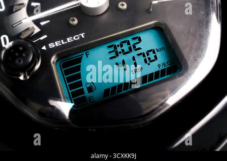 Close up of motorcycle digital speedometer with blue LCD screen showing fuel gauge, trip distance and time display, modern dashboard technology and fu Stock Photo