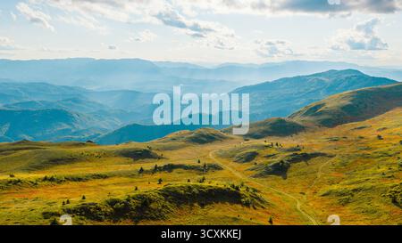 Wide mountain view with sun rays spreading through clouds and valleys Stock Photo