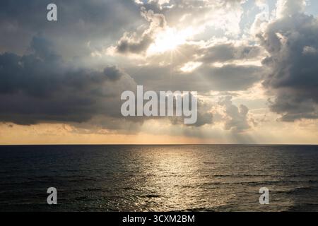 Isla Mujeres, Cancun, Mexico The sky is cloudy and the sun is shining through the clouds. The ocean is calm and the water is reflecting the sun Stock Photo