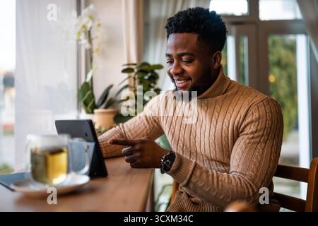 Freelancer using digital tablet to communicate online. He is sitting in bar and having video call. Stock Photo