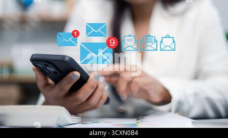 Close-up of businesswoman using smartphone with email notification icons, concept of digital communication, online messaging, and business technology Stock Photo