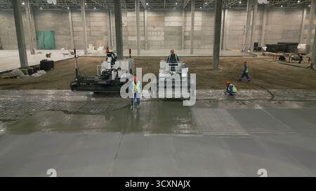 Construction workers pouring and leveling concrete floor. Clip Stock Photo