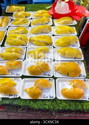 Rows of fresh Durian wrapped in plastic on display at a jalan alor street market stall prices marked on packages, smelly fruit kuala lumpur malaysia Stock Photo