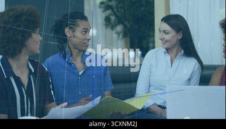Reviewing papers on coffee table, colleagues in office lounge using laptop with folder, ceramic mug Stock Photo