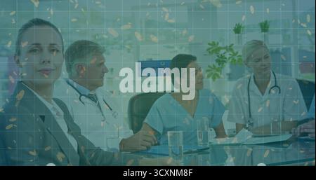 Medical and administrative team in scrubs and suits reviewing charts at table in hospital boardroom Stock Photo
