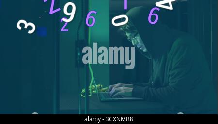 Man in hoodie typing among server racks, with laptop, yellow cables and floating digits, copy space Stock Photo