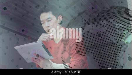 Chinese man analyzing tablet data and resting chin in modern office, with global map overlay Stock Photo