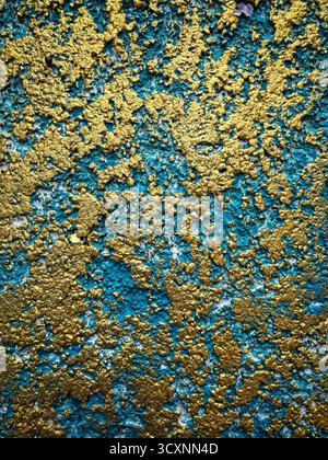 Close-up of an abstract textured wall with vibrant blue and golden paint creating a dynamic and artistic pattern Stock Photo