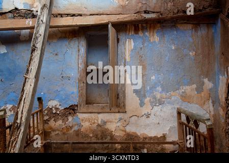 Abandoned house with blue walls surrendered to decay Stock Photo