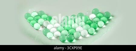 Green and white glass marbles arranged in a v shape on a light background. Stock Photo