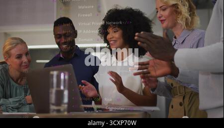 Four business casual professionals discussing code overlay around table with laptop and water glass Stock Photo