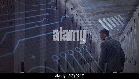 Standing technician in suit holding laptop in data center, with server racks and circuit overlay Stock Photo