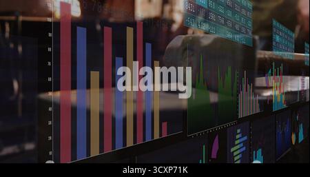 Displaying colorful bar graph with green line on computer monitors at trading desk, with keyboard Stock Photo