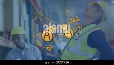 Displaying globe hovering between helmeted workers wearing safety vests in warehouse, with pallets Stock Photo