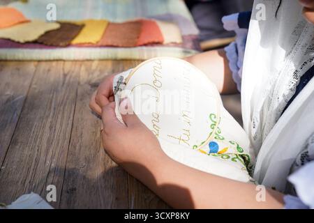 Close-up of hands working on hand embroidery with colorful thread on fabric. A detailed view of traditional craftsmanship and needlework artistry Stock Photo