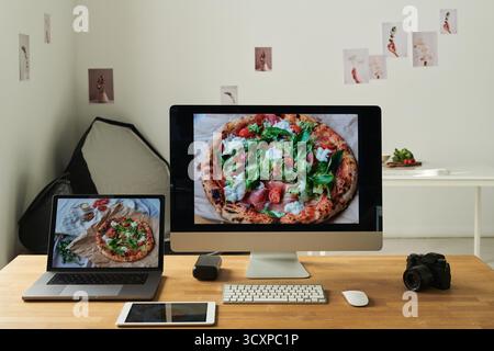 Modern Workspace Featuring Pizza Image Displayed on Computer and Laptop Screens Stock Photo