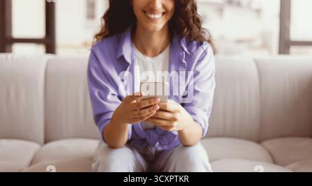 Woman Using Smartphone While Relaxing on a Comfortable Couch at Home Stock Photo
