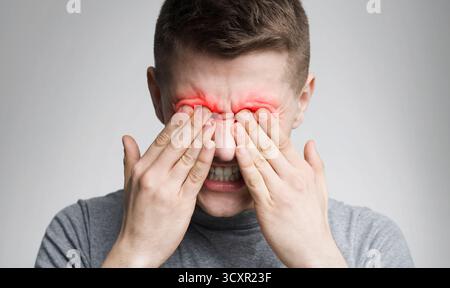Tired man suffering from eye pain, rubbing red sore zone Stock Photo
