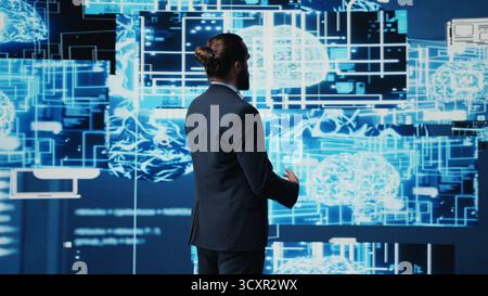 Company leader interacting with a digital AI brain symbolizing web platforms, using machine learning and algorithm development for intelligent innovation and future tech strategy. Camera B. Stock Photo