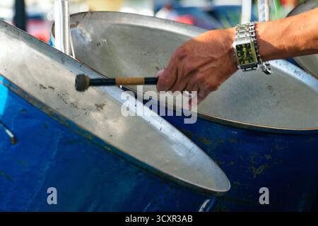 A musician performs on steel drums, filling the air with vibrant Caribbean rhythms at an outdoor event, captivating the listening crowd. Stock Photo