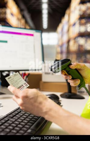 Asian male worker scanning airway bill numbers for order fulfillment and inventory control, using a scanner on shipping labels in the warehouse. Registering barcodes before distribution. Stock Photo