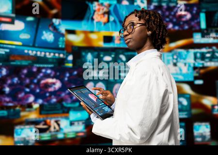 Doctor doing scientific research, analyzing human body on tablet to support medical developments. Biomedicine specialist reviewing organs on device using app, researching innovations Stock Photo