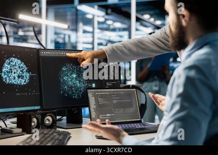 Team of admins using computer in data center office, integrating AI driven automation tools. Server farm IT specialists working together, using artificial intelligence deep learning models Stock Photo