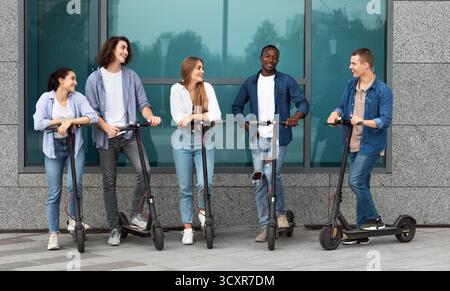 Friends having pleasant talk, riding motorized kick scooters Stock Photo