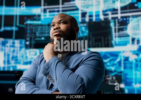Tech savvy African American specialist analyzing big data AI brain using cloud computing tools and advanced programming for virtual assistant development and automation systems. Cybernetics. Stock Photo
