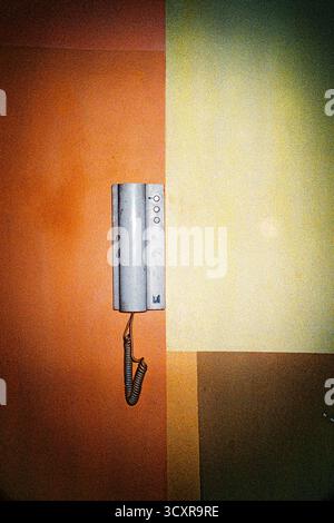Apartment intercom handset mounted on a designer wall, captured as a minimalist interior detail with vivid cross-processed analog colors. Stock Photo