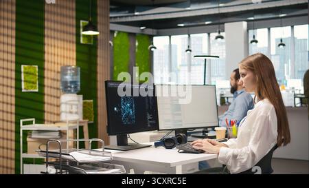 Junior dev testing generative AI machine learning algorithms and listening music at work. Young woman wearing headphones scaling productivity with AI large language model written code, camera A Stock Photo