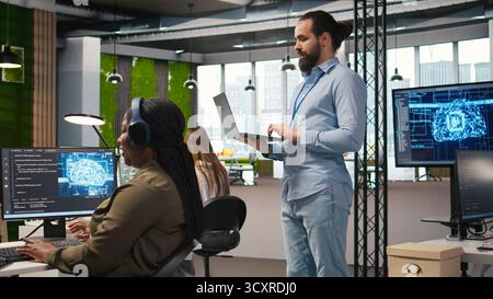Team of programmers in office developing software applications, integrating AI driven automation in operations. Developers at work debugging applications to resolve issues, camera A Stock Photo