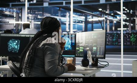 Server room specialist applies artificial intelligence technology to minimize system downtime. African American worker develops and deploys AI solutions to optimize data center equipment, camera A Stock Photo