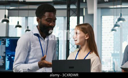Female engineer and coworker coding AI algorithms to debug software issues and improving system stability. Young woman and colleague in tech startup office configuring settings using device, camera A Stock Photo