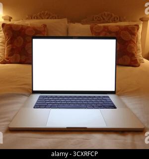 Laptop with blank screen displaying content on a bed, showing remote work, online learning, relaxation or entertainment. Mockup copyspace Stock Photo