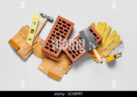 Bricks with builder belt and different tools on white background Stock Photo