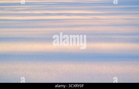 Still expanse of snow at sunset on a cold winter day. Stock Photo