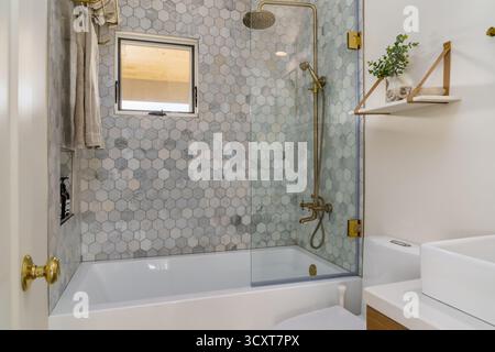 Modern bathroom in white with shower tub with hexagonal tile and gold brass fixtures Stock Photo