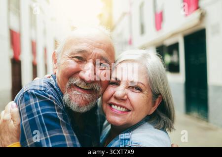 Diverse senior couple have romantic moment with background city. Elderly people hugging, relationship concept Stock Photo