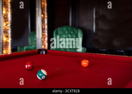 Red felt pool table with balls in a luxurious room with velvet chair and elegant mirror Stock Photo