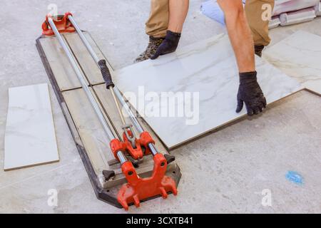 Worker using tile cutter to shape marble tiles on construction site Stock Photo