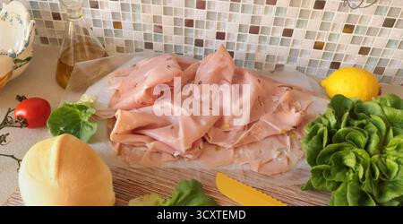 Ingredients for mortadella sandwich. Sausage, lettuce, homemade mayonnaise on kitchen table. Italian cuisine, high-quality farm-raised ingredients. Stock Photo