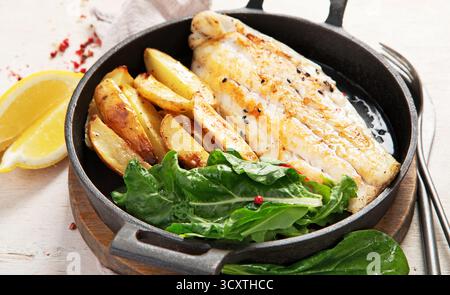 Fish dish - roasted cod, codfish fillet with baked potatoes and salad on a light background. Top view. Stock Photo