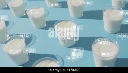 Social media icons hovering above clear plastic cups with white yogurt on blue table, with counters Stock Photo