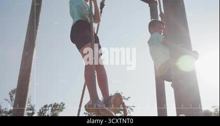 Climbing two boys scaling thick ropes on wooden structure at park, with athletic sneakers Stock Photo