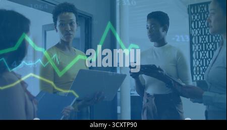 Four professionals analyzing floating charts in office, with laptop, tablets, notebook and stylus Stock Photo