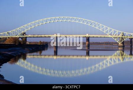 Silver Jubilee Bridge spanning the River Mersey between Runcorn and Widnes, reflected in calm water at sunrise Stock Photo