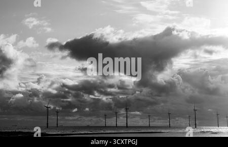 Offshore wind turbines beneath dramatic clouds in black and white Stock Photo
